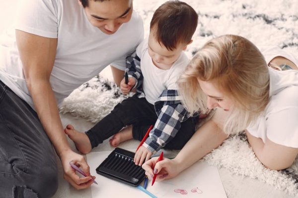 Parents and child enjoying drawing together on the floor, creating memories.